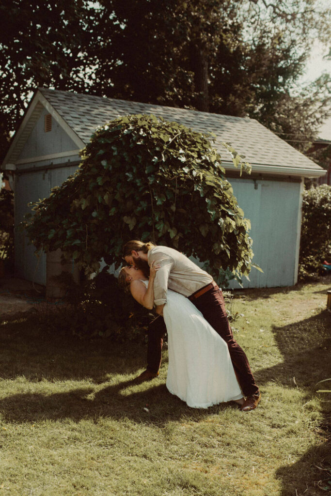 Groom dipping bride for kiss after backyard wedding ceremony