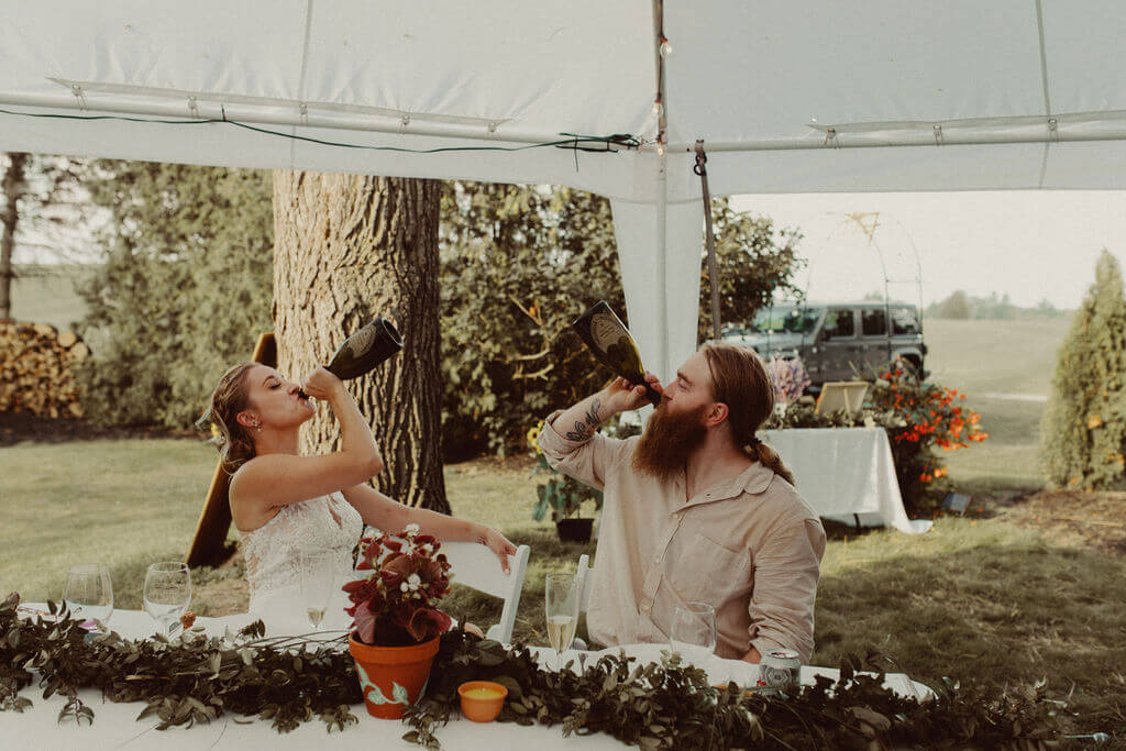 Bride and groom drink during backyard wedding reception