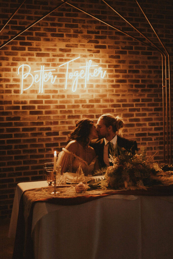 Bride and groom kiss at boho chic elopement reception table