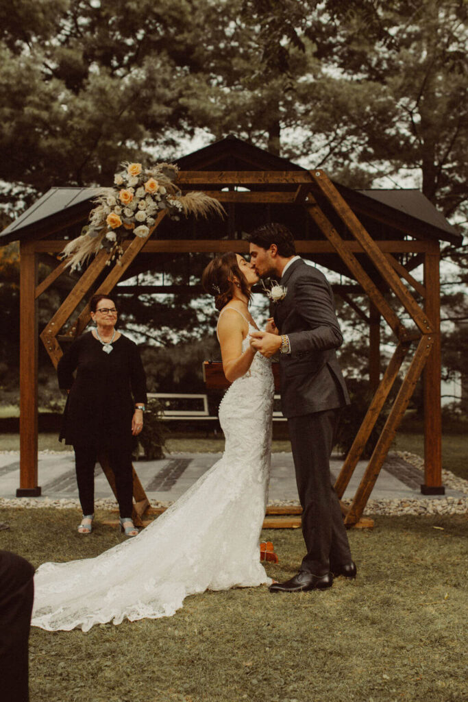 Bride and groom first kiss at backyard wedding ceremony
