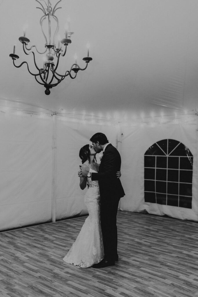 Bride and groom kiss during first dance at small backyard wedding