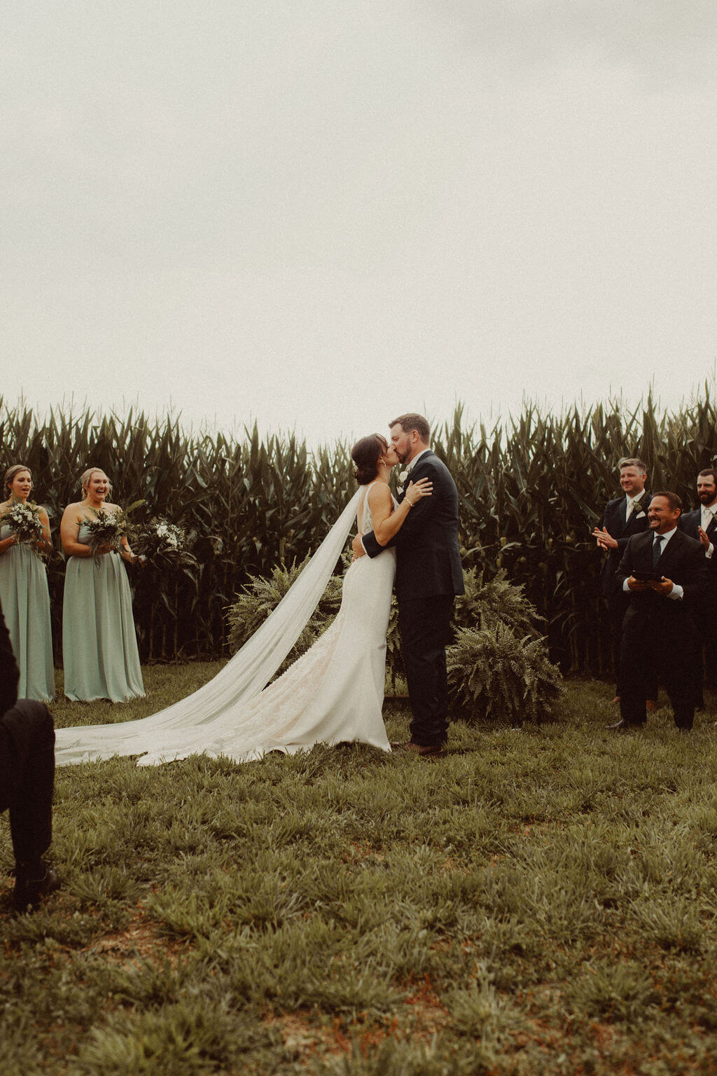 Bride and groom kiss at farm wedding ceremony