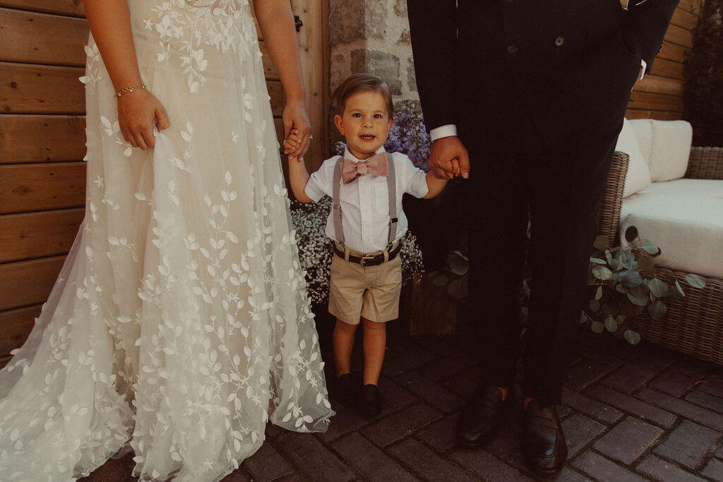 little boy holding bride and groom's hands