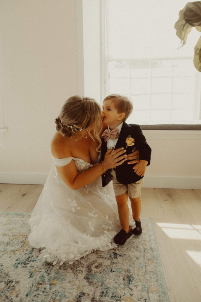 Bride kissing toddler son on her wedding day