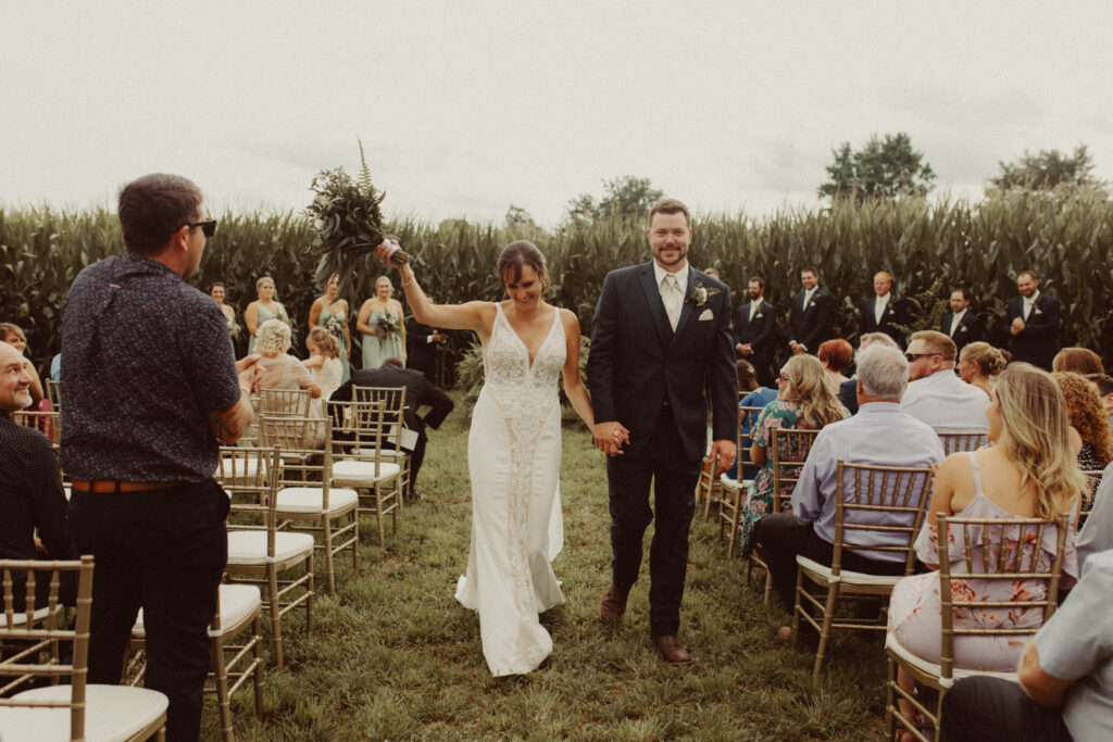 A couple walking down the aisle together after the ceremony at their intimate backyard wedding.