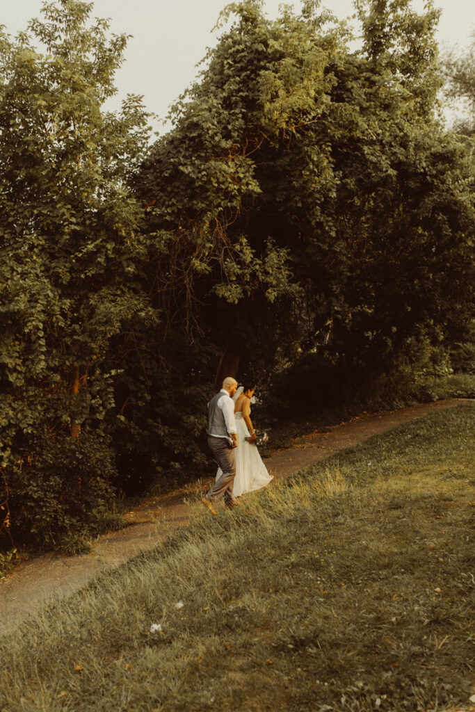 A couple is walking up a trail on their elopement day.