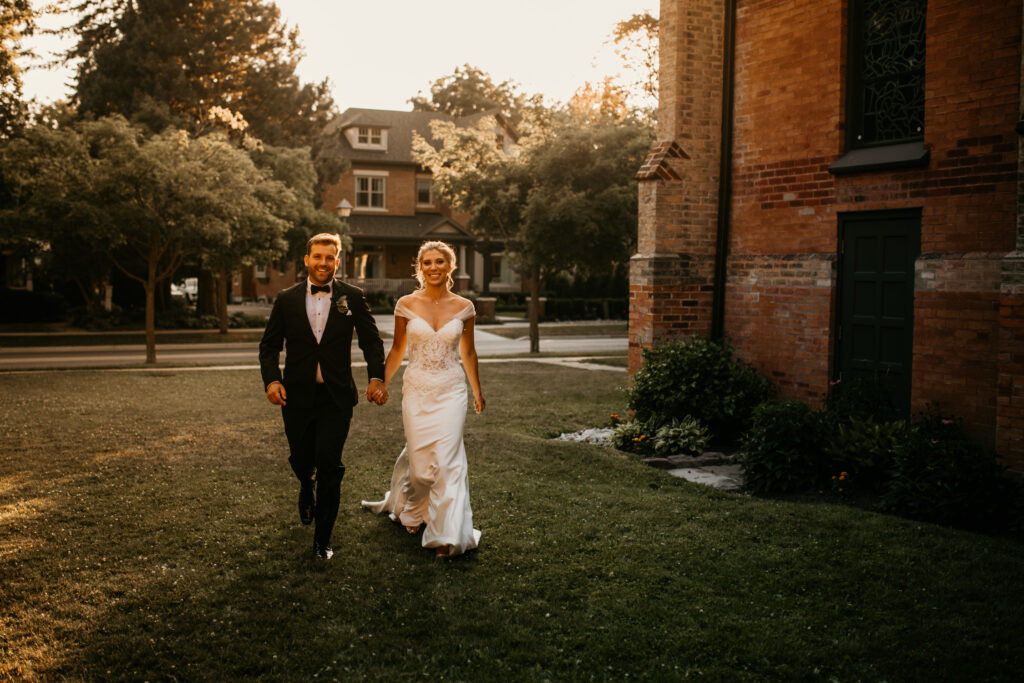 A couple is walking on the lawn in front of a church on their elopement day.