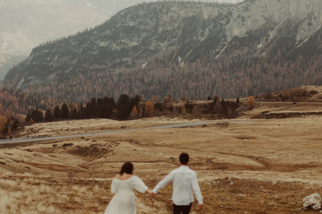 A couple walking in a field after figuring out how to plan their destination wedding in the Dolomites.