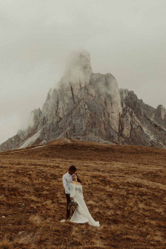 A couple who figured out how to plan a destination wedding standing in front of a mountain.